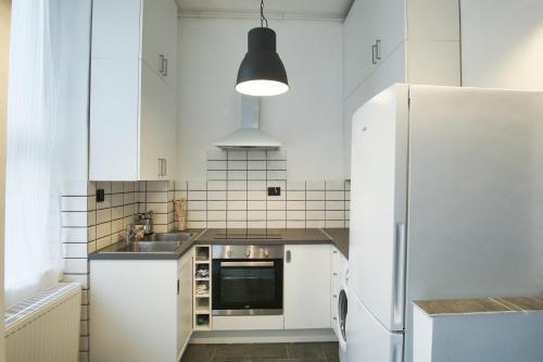 cocina con armarios blancos y nevera en Nati Apartman, en Budapest