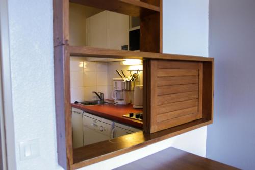une petite cuisine avec un meuble en bois dans une chambre dans l'établissement SUNWEB Résidence Les Bergers, à L'Alpe-d'Huez