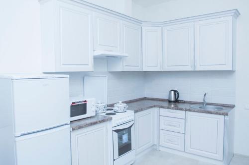 een witte keuken met witte kasten en een wastafel bij Luxury apartment Promenade Expo in Astana