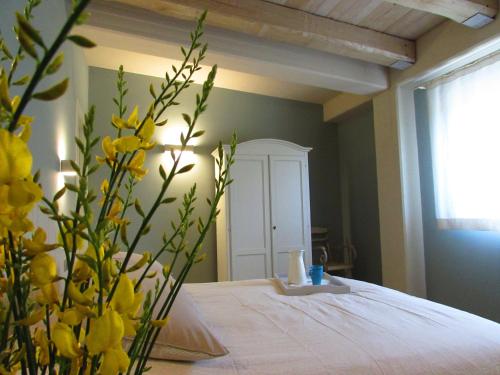 a bedroom with a bed and a vase with yellow flowers at Residenza Case Pacifici in Ascoli Piceno