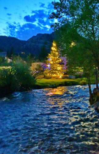 a christmas tree with lights next to a river at Murphy's River Lodge in Estes Park