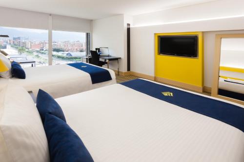 a hotel room with two beds and a flat screen tv at Wyndham Bogota in Bogotá