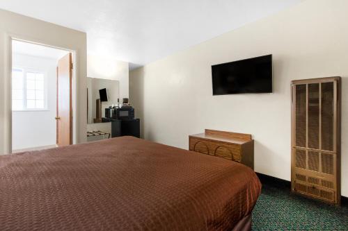 a bedroom with a bed and a flat screen tv at Eureka Town House Motel - Historic Old Town in Eureka