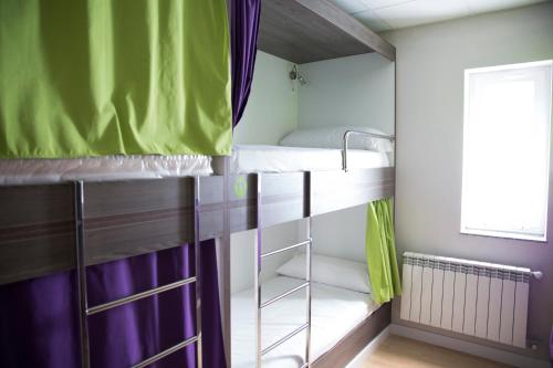 Cette chambre comprend un lit superposé avec des rideaux violets et verts. dans l'établissement Albergue Camiño Do Sar, à Padrón