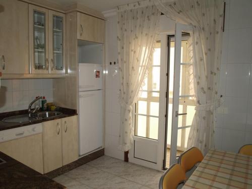 ビラノーバ・デ・アロウサにあるApartamento La Basellaのキッチン(冷蔵庫、テーブル付)、窓が備わります。