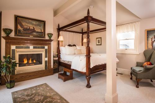 a bedroom with a canopy bed and a fireplace at Captain Farris House in South Yarmouth