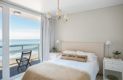 a bedroom with a bed and a balcony with the ocean at 457 Gascon in Mar del Plata