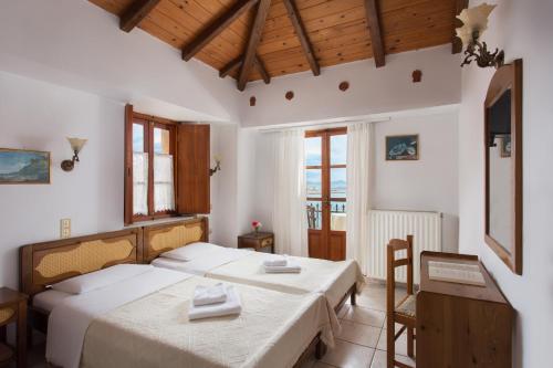 um quarto com 2 camas, uma mesa e cadeiras em Petrino Guesthouse em Monemvasia