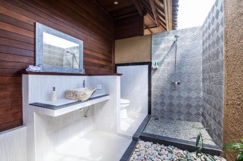 a bathroom with a shower and a toilet and a mirror at The Cubang Hut's Lembongan in Nusa Lembongan