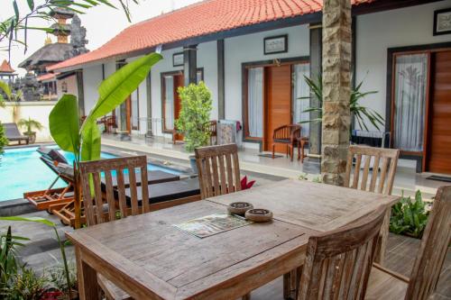 Nyoman Guesthouse Berawa Canggu في تشانغو: طاولة وكراسي خشبية أمام المنزل