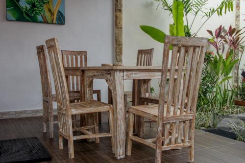 mesa de madera, 4 sillas, mesa y sillas en Nyoman Guesthouse Berawa Canggu, en Canggu
