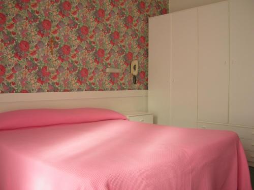 a bedroom with a pink bed and a floral wallpaper at Hotel Gioiella Depandance in Bellaria-Igea Marina