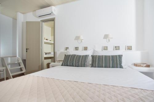a white bedroom with a large white bed with striped pillows at Natura Villas Paros in Molos Parou