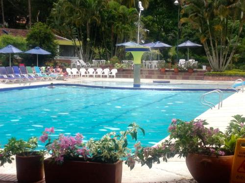 a large swimming pool with chairs and umbrellas at Hotel Hacienda El Diamante in Villeta