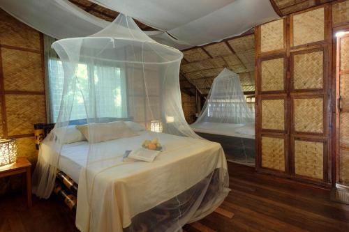 a bedroom with a bed with a mosquito net at Amami Beach Resort in Puerto Galera