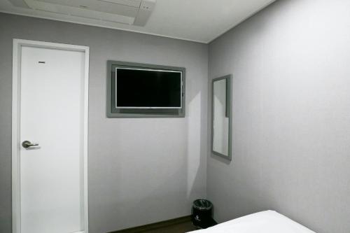 a bedroom with a flat screen tv on the wall at Philstay Myeongdong Station in Seoul