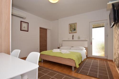 a bedroom with a bed with a green blanket on it at Apartment Smokrovic in Starigrad