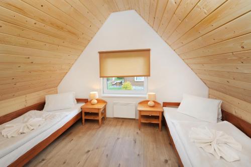 Cette chambre comprend 2 lits et une fenêtre. dans l'établissement APLEND Chaty Tatry Holiday, à Veľký Slavkov