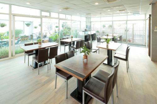 un restaurante con mesas, sillas y ventanas grandes en Cambridge Hotel - Yung Kang, en Yongkang