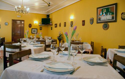 un comedor con mesas y sillas y copas de vino en Hostal Restaurante La Cepa, en Cariño