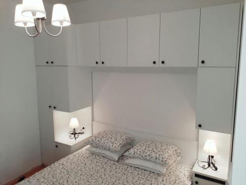a white bedroom with a bed with two pillows at Apartmani Vitturi in Kaštela