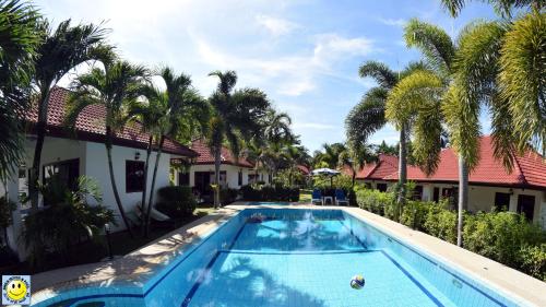 a swimming pool in front of a house with palm trees at D&K Smiley Phuket Resort in Rawai Beach