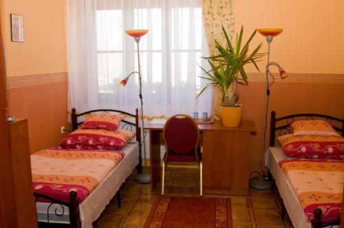 2 camas en una habitación con mesa y ventana en Bátor Park Panzió en Nyírbátor