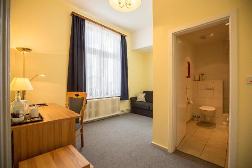 a room with a desk and a room with a bathroom at Hotel Graf Waldersee in Borkum