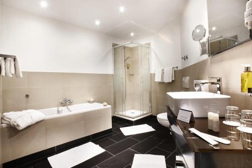y baño con bañera, aseo y lavamanos. en Hotel Kiel by Golden Tulip, en Kiel