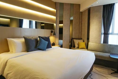 a bedroom with a large white bed and a couch at The Harbourview - Chinese YMCA of Hong Kong in Hong Kong
