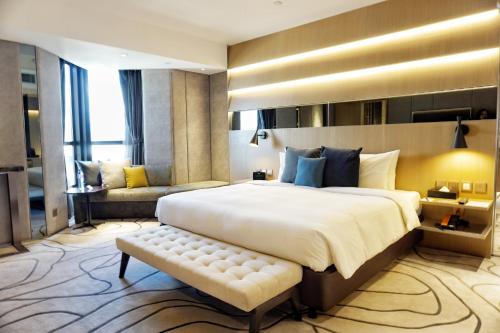 a large bedroom with a large bed and a bench at The Harbourview - Chinese YMCA of Hong Kong in Hong Kong