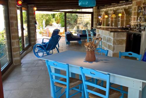 a kitchen with a blue table and chairs on a patio at VILLE GIRASOLI "VILLA NELLA BAIA" with PRIVATE SWIMMING POOL in Tricase