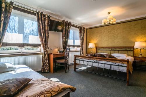 a hotel room with two beds and a desk and a window at Resort Strzelnica in Kochcice