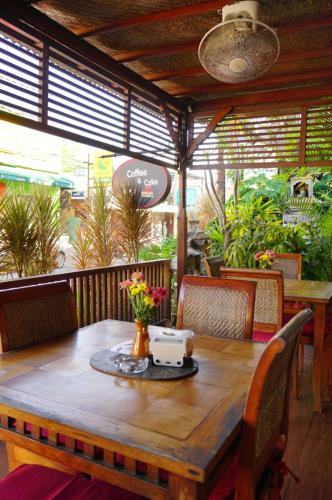 a wooden table and chairs in a restaurant with a table and flowers at Yulia 2 Homestay Sanur in Sanur
