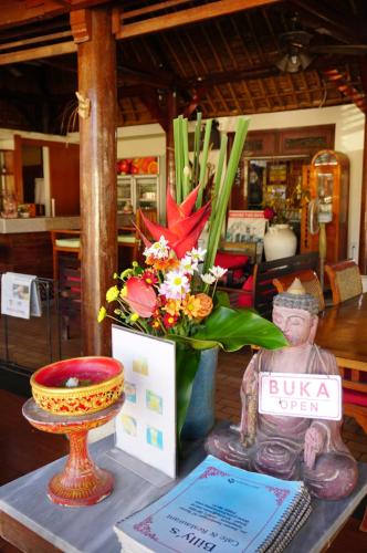 a table with a vase of flowers and a statue at Yulia 2 Homestay Sanur in Sanur