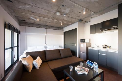 a living room with a couch and a kitchen at A Good Day Fukuoka Riverside in Fukuoka