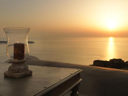una candela in un vaso di vetro su un tavolo vicino all'oceano di OIA UNIQUE HOMES by K&K a Oia