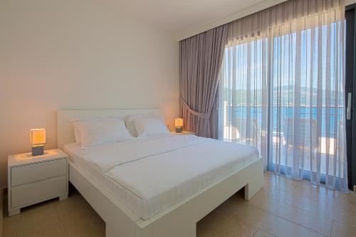 een slaapkamer met een groot bed en een groot raam bij Villa Krasici in Tivat