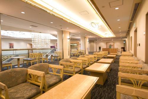 大阪市にある新大阪ワシントンホテルプラザの木製のテーブルと椅子のあるレストラン、カフェテリア