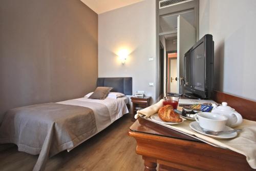 a bedroom with a bed and a table with a tray of food at Hotel Terme Salvarola in Sassuolo