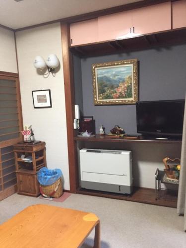 a living room with a flat screen tv and a table at Daikokuya Mt.Fuji in Fujiyoshida