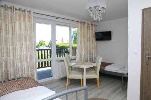 a bedroom with a bed and a table and a balcony at Gościniec w Malborku in Malbork