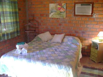 een slaapkamer met een bed en een bakstenen muur bij Posada del Bosque in Rivera