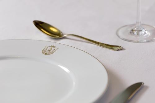 a table with a plate and a spoon and glasses at Hotel Brunnenhaus Schloss Landau in Bad Arolsen