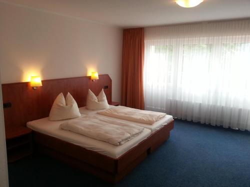 Schmucker Jäger - Hotel Garni في هانوفيرش موندن: غرفة نوم بسرير وملاءات بيضاء ونافذة