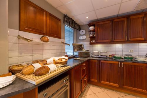 a kitchen with wooden cabinets and breads on a counter at Enter Amalie Hotel in Tromsø