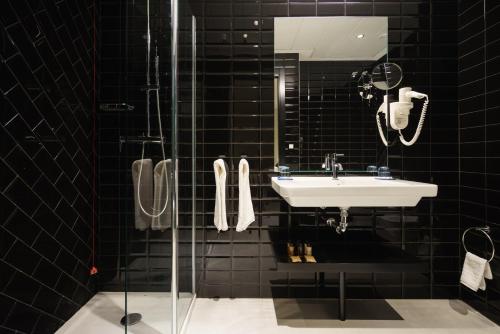 baño de azulejos negros con lavabo y ducha en Costa del Sol Torremolinos Hotel, en Torremolinos