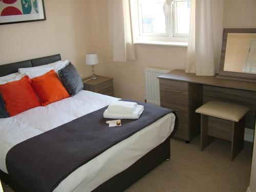 a bedroom with a bed with orange pillows and a desk at Thistle Cottage in Mildenhall