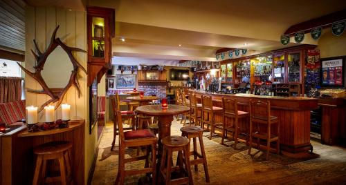 a bar with wooden stools and tables in a restaurant at Horse & Hound in Delgany