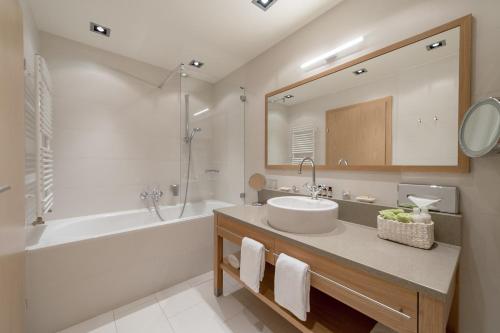 y baño con lavabo, bañera y espejo. en La Pura Women's Health Resort Kamptal, en Gars am Kamp